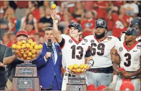  ?? Rhona Wise/USA TODAY Sports ?? Georgia Bulldogs quarterbac­k Stetson Bennett (13) throws oranges as he celebrates with the Orange Bowl Trophy after defeating the Michigan Wolverines in the Orange Bowl college football CFP national semifinal game at Hard Rock Stadium.