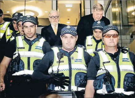  ?? DARRIAN TRAYNOR / GETTY ?? Pell (arriba, a la derecha) es escoltado por la policía del despacho de su abogado al tribunal en Melbourne