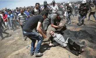  ?? Khalil Hamra / Associated Press ?? A Palestinia­n man falls on the ground Monday after being shot by Israeli troops during a protest at the Gaza Strip's border with Israel. Protesters threw stones and flaming kites at the troops.