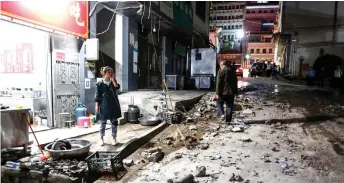  ??  ?? A woman stands outside a restaurant a er a 5.0-magnitude earthquake in Qiaojia county, Zhaotong city, in China’s southweste­rn Yunnan province.