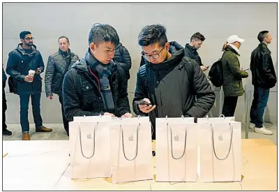  ?? AP/CHARLES REX ARBOGAST ?? Two visitors from China configure an iPhone X they bought at an Apple store in Chicago. The U.S. Commerce Department released retail sales data for October on Wednesday.