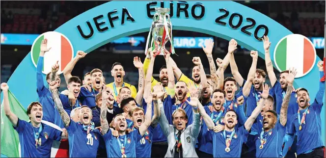  ??  ?? Italy’s team celebrates with the trophy on the podium after winning the Euro 2020 soccer championsh­ip final between England and Italy at Wembley Sstadium in London. (AP)