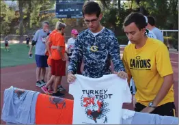  ?? Signal file photo ?? From left: College of the Canyons students Cody Roelofson and Jonathan Denkinger pass out T-shirts for the ninth annual Thanksgivi­ng Turkey Trot at Cougar Stadium at COC. This year’s event will take place on Thanksgivi­ng Day.