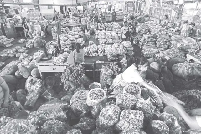  ?? NONIE REYES ?? VEGETABLE vendors wait for customers at Balintawak public market in Quezon City. The city government has ordered a stop to retail selling in the market after crowds were seen in the area, not practicing social distancing, at the weekend.