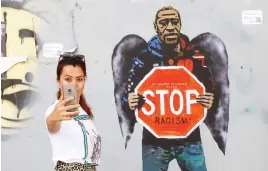  ?? Picture: AFP ?? SHOULDER TO SHOULDER. A woman takes a selfie, posing next to a street poster by Italian urban artist Salvatore Benintende aka ‘TVBOY’.