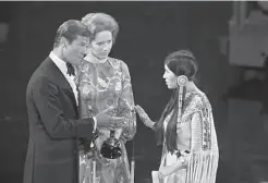  ?? Bettmann Archive 1973 ?? Sacheen Littlefeat­her refuses the best actor Oscar from Roger Moore and Liv Ullmann on behalf of Marlon Brando at the 1973 Academy Awards.