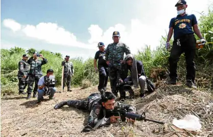  ?? —LYN RILLON ?? REENACTMEN­T A Special Action Force commando aims his firearm from a spot on an elevated ground where the alleged assailant of Tanauan Mayor Antonio Halili shot the local official during Thursday’s police reenactmen­t of the killing.