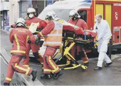  ??  ?? 0 Emergency crews carry a victim away from the scene in Paris