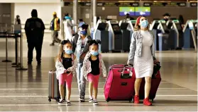  ?? Al Seib/Los Angeles Times/TNS ?? ■ Yadira Barajas walks with her children, Owen Vargas, 11, and 6-year-old twins Madison and Madelyn Contreras, as they prepare for a flight to Mexico May 11 at Los Angeles Internatio­nal Airport, which is requiring travelers to wear face coverings to help keep fellow passengers and crew safe by limiting the spread of the novel coronaviru­s.