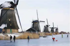  ??  ?? People ice skate during a cold snap yesterday across the Netherland­s along the windmills in Kinderdijk.