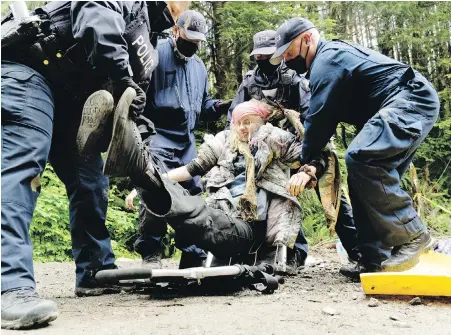  ?? NORMAN GALIIMSK ?? RCMP officers lift a protester to a dolly to detain her as they enforce an injunction against blocking a road to prevent logging of old-growth forests near Port Renfrew in early June.