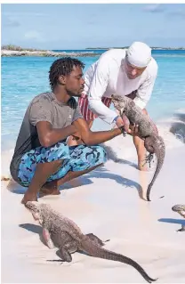  ?? FOTO: SASCHA RETTIG ?? Tour-Guide Captain Sugar (l.) hebt einen der Leguane hoch, die Allen’s Cay bewohnen.