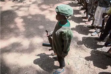  ??  ?? Tainted childhood:
A newly released child soldier standing with a rifle during their release ceremony in Yambio, South Sudan. — AFP