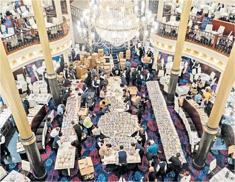  ??  ?? The crew of Royal Caribbean’s Mariner of the Seas cruise ship pack food in the dining room at sea off Freeport, above, as part of the company’s operation to supply 20,000 daily meals to islanders. Left: a boat washed ashore on Elbow Cay in the Abaco islands