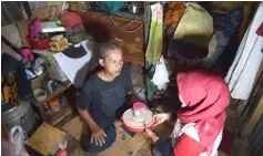  ??  ?? This picture shows elderly man (left) receiving a container with uneaten food from a volunteer of the programme ‘A Blessing to Share’, in a slum area in Jakarta.