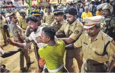  ?? PTI ?? Police personnel detain the devotees who were staging Namajapa protest against the restrictio­ns.