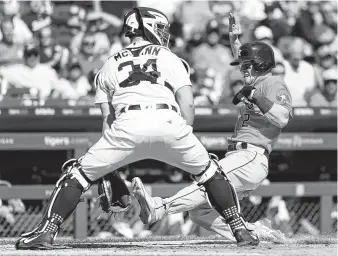  ?? Paul Sancya / Associated Press ?? Alex Bregman, right, scores the 100th run of his season Wednesday in the fifth inning. Tigers catcher James McCann has the closest vantage point for the milestone moment.