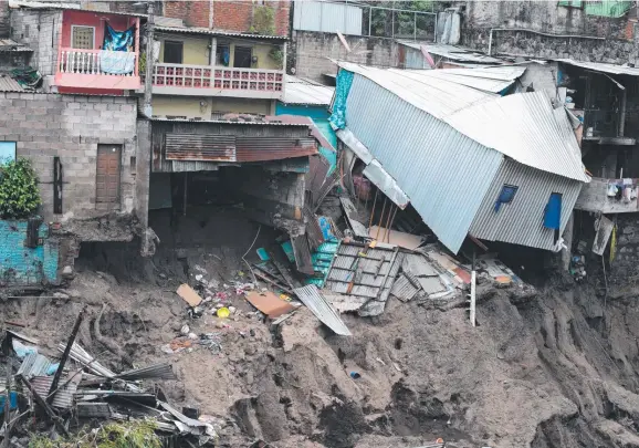  ??  ?? Houses perched on the edge of a landslide caused by Tropical Storm Amanda in El Salvador which has forced thousands into refuges (below). Picture: AFP