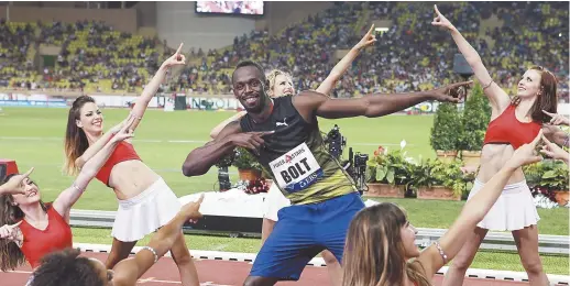  ??  ?? Usain Bolt prend sa célèbre pose, imité cette fois par des meneuses de claques. - Associated Press