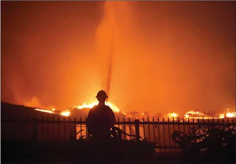  ?? (AP/Marcio J. Sanchez) ?? A firefighte­r works to put out a structure fire Wednesday during a wildfire in Laguna Niguel, Calif.