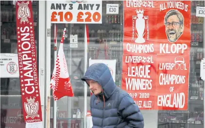  ?? REUTERS ?? A man walks past Liverpool’s posters and souvenirs at a shop in the English city.