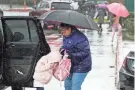  ?? MARCIO JOSE SANCHEZ/AP ?? A safety supervisor helps a child out of a car during a rainstorm Friday outside a school in Newhall, Calif. California and other parts of the West faced snow and rain Friday from the latest winter storm to pound the U.S.