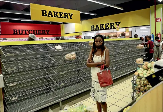  ?? AP ?? A woman walks past almost empty bread shelves in a Harare shop. As Zimbabwe plunges into its worst economic crisis in a decade, prices are spiking and long queues forming at shops and petrol stations.