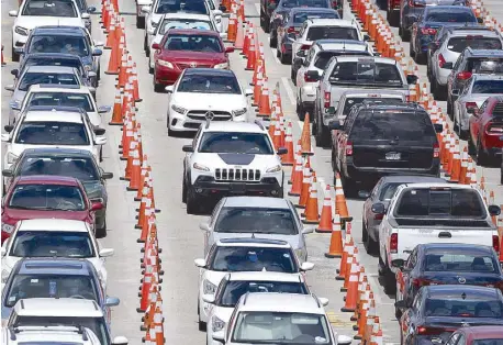  ??  ?? Cars wait in lines at a coronaviru­s testing site outside Hard Rock Stadium in Miami Gardens, Florida on Friday.