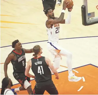  ?? PATRICK BREEN/THE REPUBLIC ?? The Suns’ Deandre Ayton (22) makes a layup past Rockets’ Kelly Olynyk (41) during the first half Tuesday at the Phoenix Suns Arena.