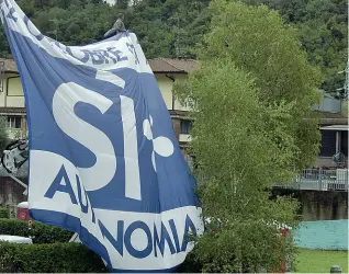  ??  ?? Proclami Sopra, le prove del bandierone di 10 metri per 10 con il sì all’autonomia. A destra, il palco con la scritta «Salvini premier» e uno dei tanti stand allestiti dai militanti