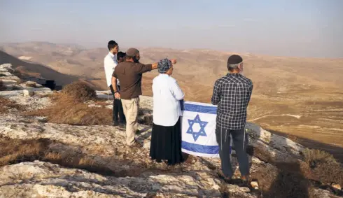  ?? ?? A SETTLER LEADER holds an Israeli flag during a scouting mission to find new hilltops for settlement­s near Kokhav Hashahar, in the Israeli-occupied West Bank on November 6. The 7,00,000 illegal Jewish settlers in the West Bank set the agenda for this election: the expropriat­ion of more Palestinia­n land.