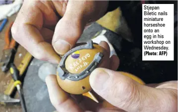  ?? (Photo: AFP) ?? Stjepan Biletic nails miniature horseshoe onto an egg in his workshop on Wednesday.