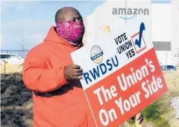  ?? JAY REEVES/AP 2021 ?? Michael Foster of the Retail, Wholesale and Department Store Union holds a sign outside an Amazon facility where labor is trying to organize workers in Bessemer, Ala.