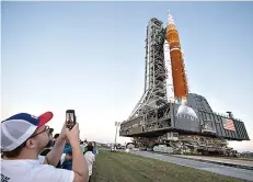  ?? The Associated Press ?? Invited guests and NASA employees take photos as NASA’s Space Launch System (SLS) rocket with the Orion spacecraft aboard is rolled out of High Bay 3 of the Vehicle Assembly Building for the first time March 17 at the Kennedy Space Center in Cape Canaveral, Fla. On Wednesday, the 53rd anniversar­y of the Apollo 11 moon landing, NASA said it’s shooting for a late August test launch of its giant, new moon rocket.