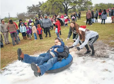  ?? Photos by Matthew Busch / Contributo­r ?? John Cantu rides on a snow slide with son Jovonny Cantu, 4, as part of a celebratio­n for the 50th anniversar­y of Elf Louise.