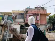  ?? PHOTO : D. R. ?? Une jeune Palestinie­nne passe devant une maison de Cheikh Jarrah, quartier de JérusalemE­st occupé et annexé par Israël, au-dessus de laquelle on peut voir une étoile de David et un drapeau israélien, le 5 mai 2021