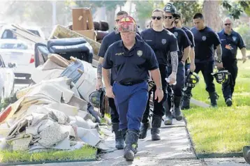  ?? LM OTERO/AP ?? Firefighte­rs conduct a door-to-door safety check Thursday for residents of a neighborho­od hit by floods in Houston.