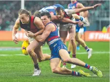  ??  ?? Essendon’s Mason Redman goes to ground under pressure from Bulldog Laitham Vandermeer. Picture: Steve Bell