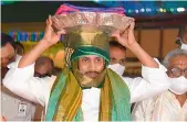  ??  ?? Andhra Pradesh Chief Minister Y.S. Jagan Mohan Reddy carries a pair of new PattuVastr­ams on his head and goes in a procession to the main shrine to present them to Lord Venkateswa­ra on Wednesday.