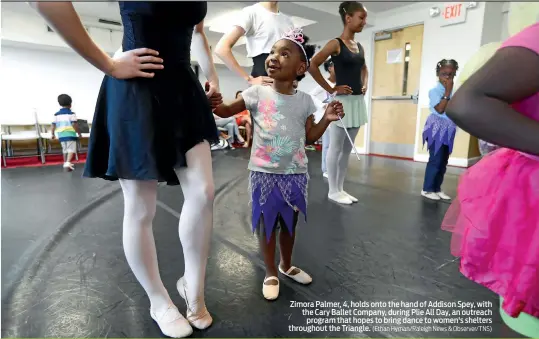  ?? (Ethan Hyman/Raleigh News & Observer/TNS) ?? Zimora Palmer, 4, holds onto the hand of Addison Spey, with the Cary Ballet Company, during Plie All Day, an outreach program that hopes to bring dance to women's shelters throughout the Triangle.