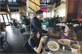  ?? Mel Melcon Los Angeles Times ?? MIKE LUNA serves Bahar Sheikhreza­e and Ciara Arellano at Frida, a Mexican restaurant at the Americana. He says the lottery wins are “like a competitio­n.”