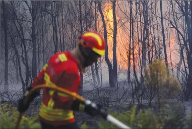  ?? Associated Press photo ?? Portuguese firefighte­rs work to stop a forest fire from reaching the village of Figueiro dos Vinhos in central Portugal, Sunday. Portugal's president says the country’s pain “knows no end” as it mourns at least 61 people killed.