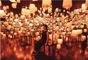  ??  ?? A staff member sits at an interactiv­e digital installati­on ‘Fire / Forest and Spiral of Resonating Lamps in the Forest’.