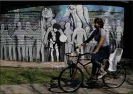  ?? NATACHA PISARENKO — THE ASSOCIATED PRESS ?? A woman cycles past Lionel Messi’s school “Escuela General Las Heras” primary school in Rosario, Argentina. The mural featuring Messi was painted by the school’s students and teachers with the help of local artist Ruben Perez Barrios.