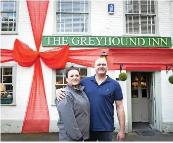  ?? Daniel Jae-Webb/SWNS ?? Landlord and landlady of The Greyhound Inn, Graeme and Nikki McNulty, with the pub wrapped as a giant Christmas present – and not draped in the England flag