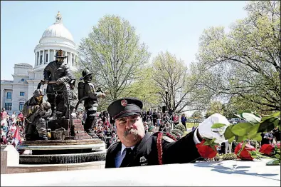  ?? Arkansas Democrat-Gazette/THOMAS METTHE ?? Little Rock Firefighte­r Charles Austin places a rose as the names of fallen firefighte­rs are called out Saturday during the Arkansas Fallen Firefighte­rs Memorial Service at the state Capitol in Little Rock.