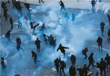  ?? AURELIEN MORISSARD/AP ?? Youths kick tear gas canisters during a demonstrat­ion Tuesday in Paris. Hundreds of thousands of demonstrat­ors across France took part in the biggest mobilizati­on yet to protest against President Emmanuel Macron’s government’s plan to raise the retirement age from 62 to 64. The French, polls show, are overwhelmi­ngly opposed to retiring later.