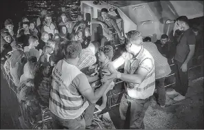  ?? AP ?? In a photo provided by the Romanian border police, officers carry a child early Wednesday as they help rescue migrants in the Black Sea port of Constanta, Romania.