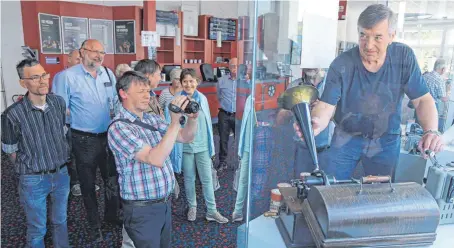  ?? FOTO: GERD MÄGERLE ?? Adrian Kutter (r.) demonstrie­rt den Teilnehmer­n des Kongresses die Funktionsw­eise eines Phonograph­en aus dem Jahr 1903.