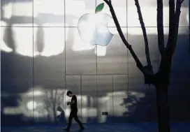  ??  ?? Booming field: A man uses his phone as he walks past an Apple store in Beijing. Engineers at Apple are racing to catch their peers at Amazon. com Inc and Alphabet Inc in the booming field of AI. — Reuters